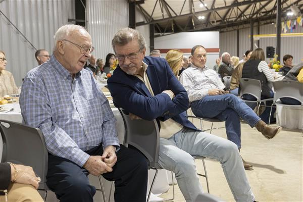 Ronny Garrett and Dr. Terry Graham in conversation. Charlie Collat, Jr. enjoys the performance of Three on a String.